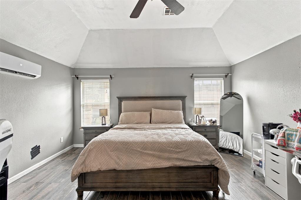 Bedroom with a dark wood bed, vaulted ceiling, and windows on either side.