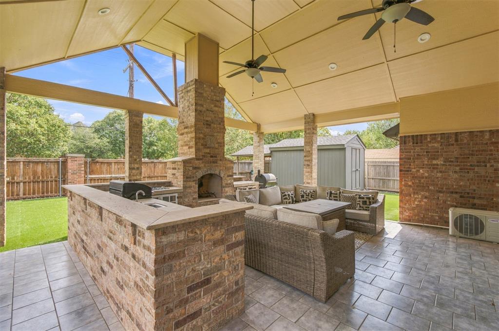 Covered patio with a brick outdoor kitchen, fireplace, and wicker seating.