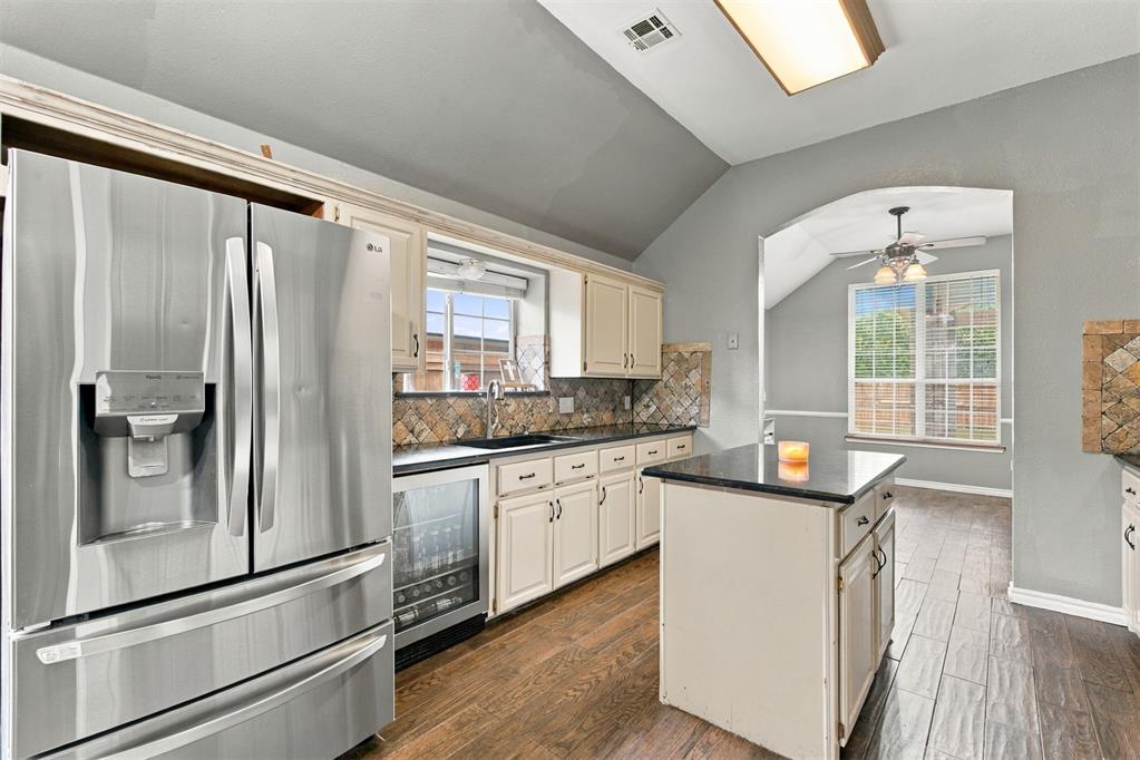 Kitchen with stainless steel appliances, a central island, and an arched opening to a dining area.