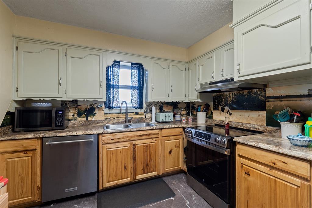 Kitchen with white upper cabinets, wood lower cabinets, granite counters, and stainless steel appliances.