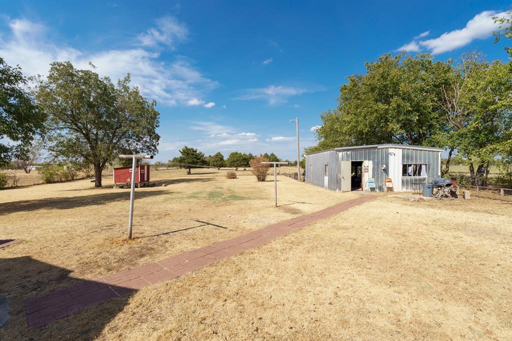 Spacious yard with a brick walkway, clothesline posts, and detached metal outbuilding