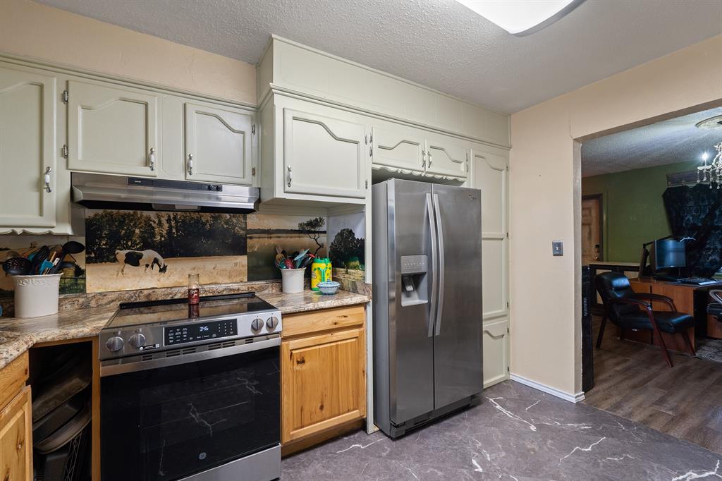 Kitchen with white cabinets, a black range, stainless steel refrigerator, and stone-look counters.