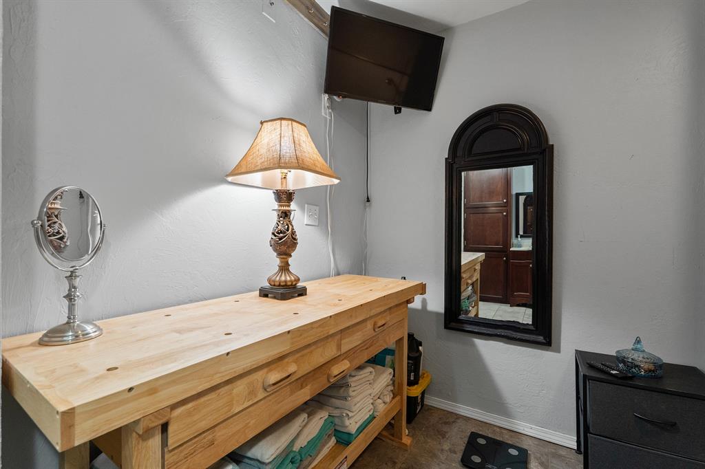 Laundry room with a long wooden folding counter, open towel shelves, and wall-mounted television.