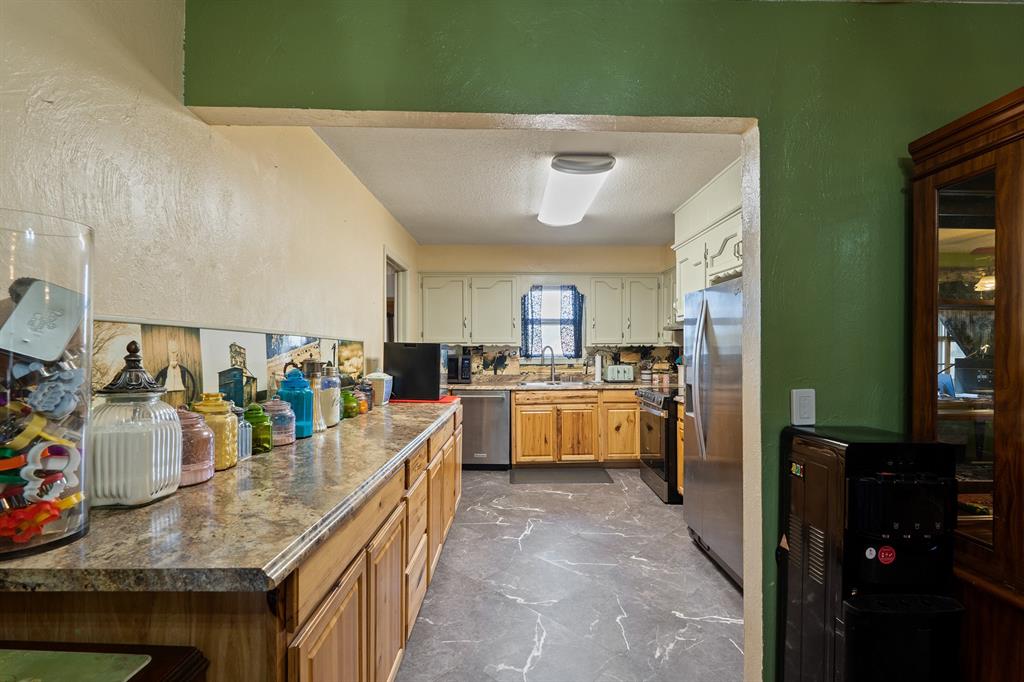 Kitchen with wood cabinets, long stone countertops, and stainless steel appliances.