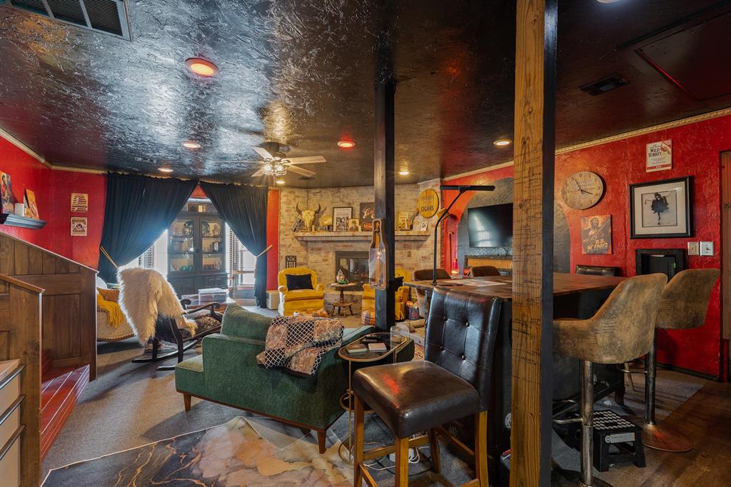 Living room and bar with red walls, exposed wooden posts, and eclectic seating.