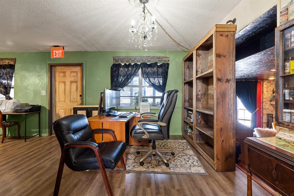 Furnished home office with green walls, wooden shelving, and black leather chairs.