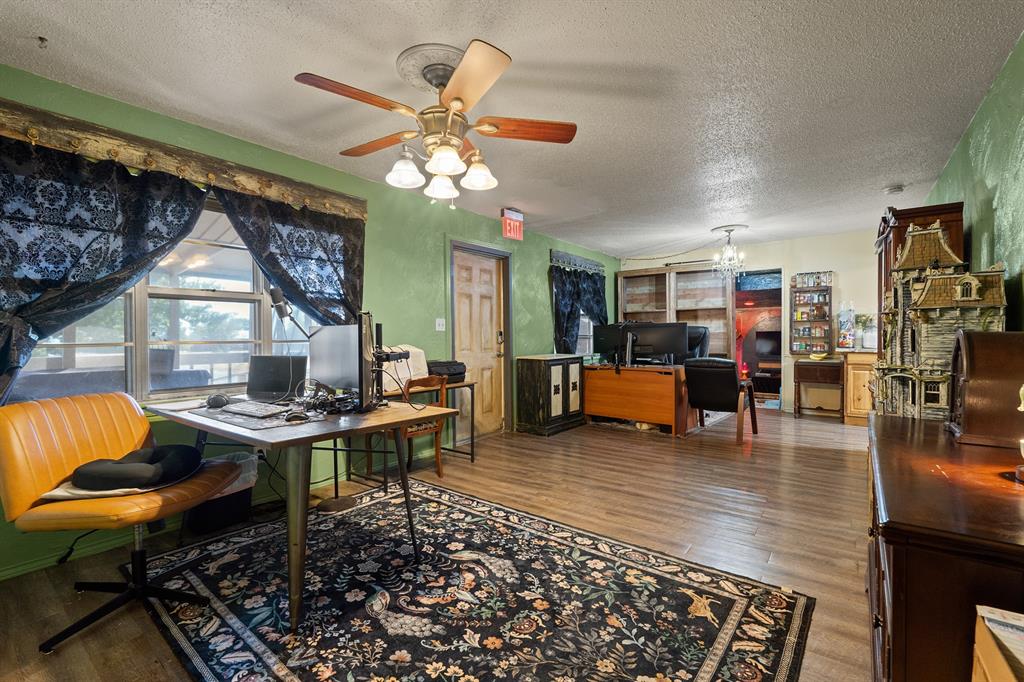Home office with computer desks, green walls, dark patterned curtains, and a large floral rug.