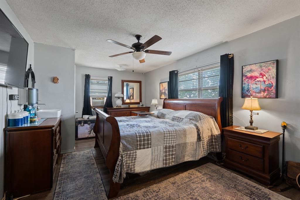 Bedroom with a large wooden bed, patterned quilt, dark curtains, and matching bedside furniture.