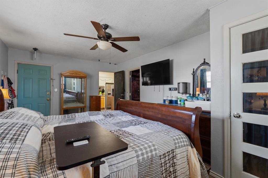 Furnished bedroom with plaid bedding, a dark wood headboard, and a wall-mounted television.