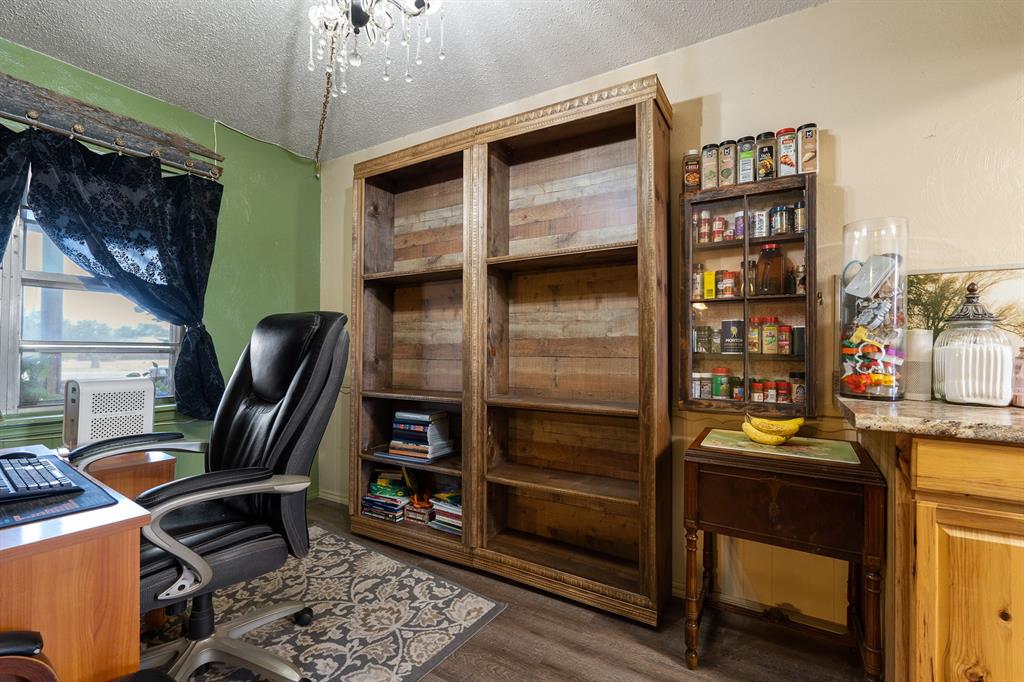 Home office with rustic wood shelving, a black desk chair, and a window with dark curtains.
