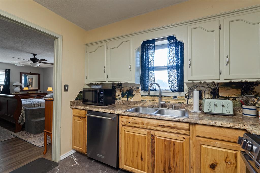 Kitchen with wood lower cabinets, white upper cabinets, a double sink, and a stainless steel dishwasher.