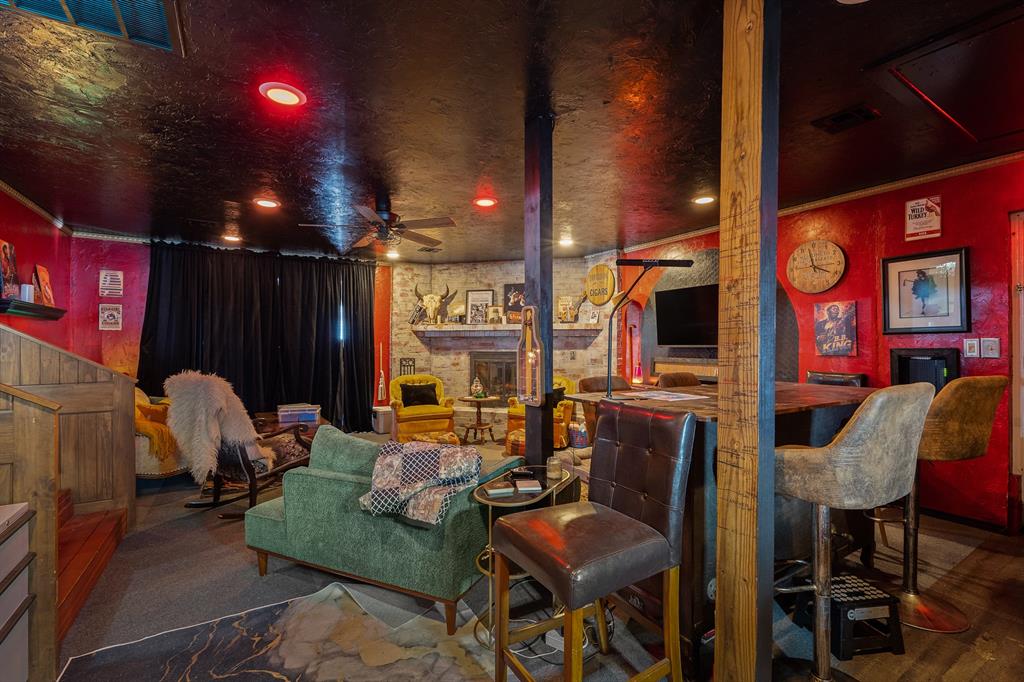Furnished lounge with red walls, stone accents, a bar counter, and varied seating.