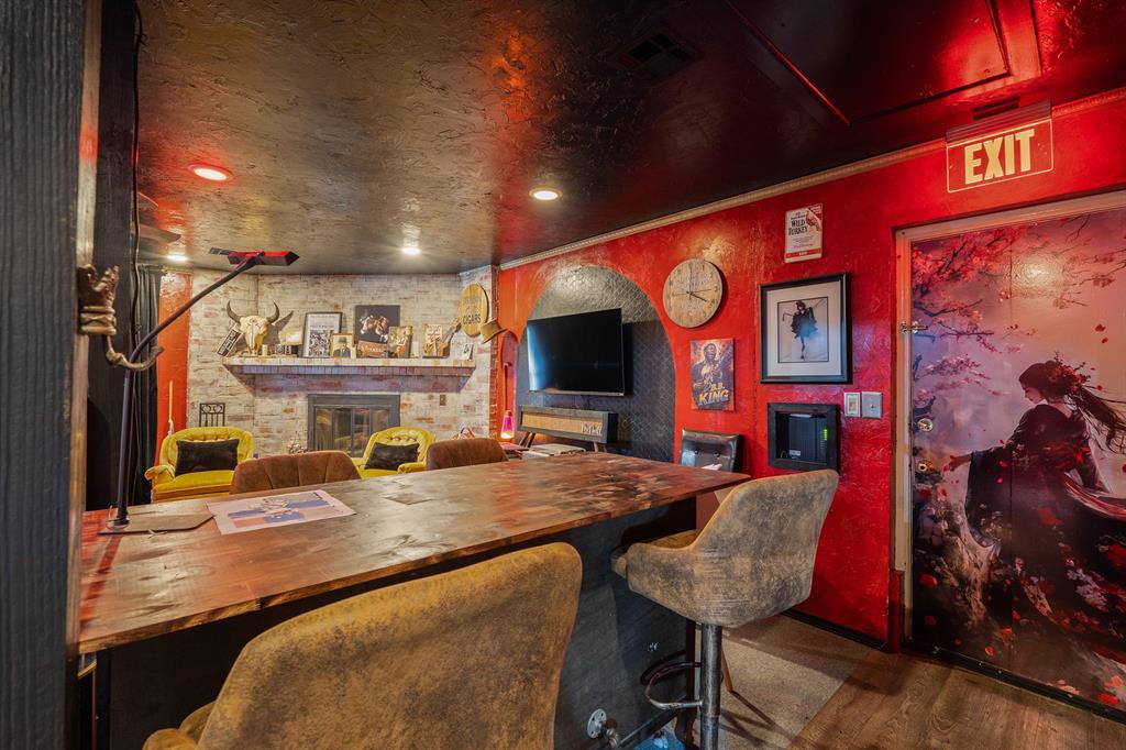 Entertainment room with a long wood table, stone fireplace, wall-mounted TV, and red walls.