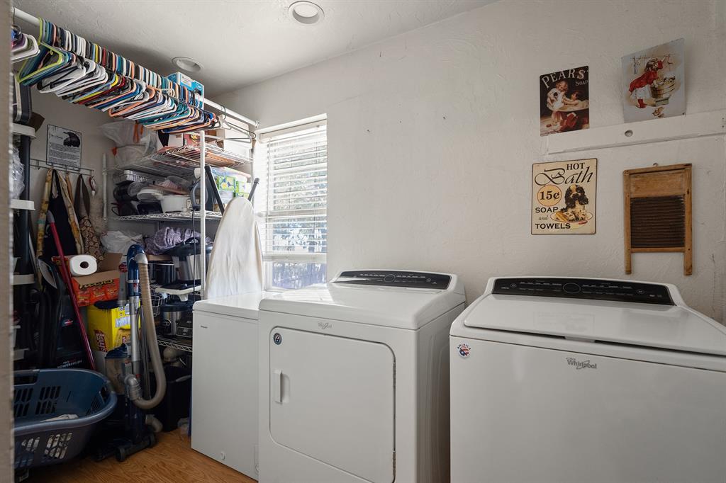 Laundry room with washer and dryer beside open storage shelves and a window.