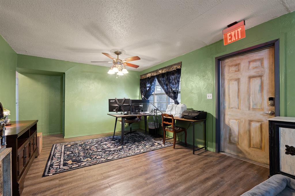 Home office with computer monitors, patterned rug, green walls, and ceiling fan.