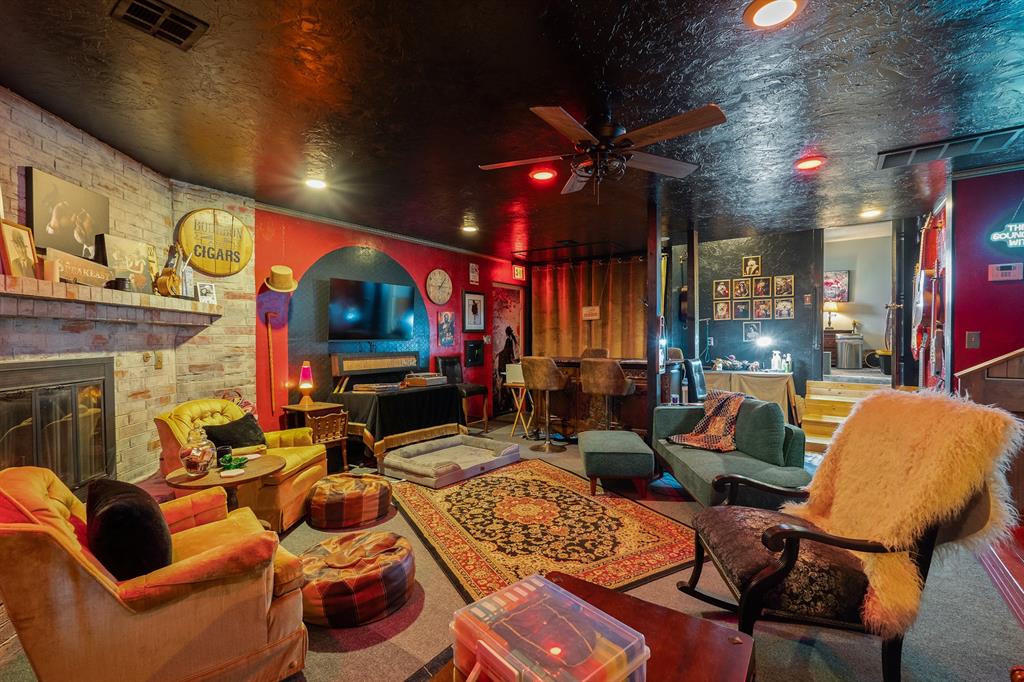 Entertainment lounge with a brick fireplace, television, colorful seating, and patterned rug.