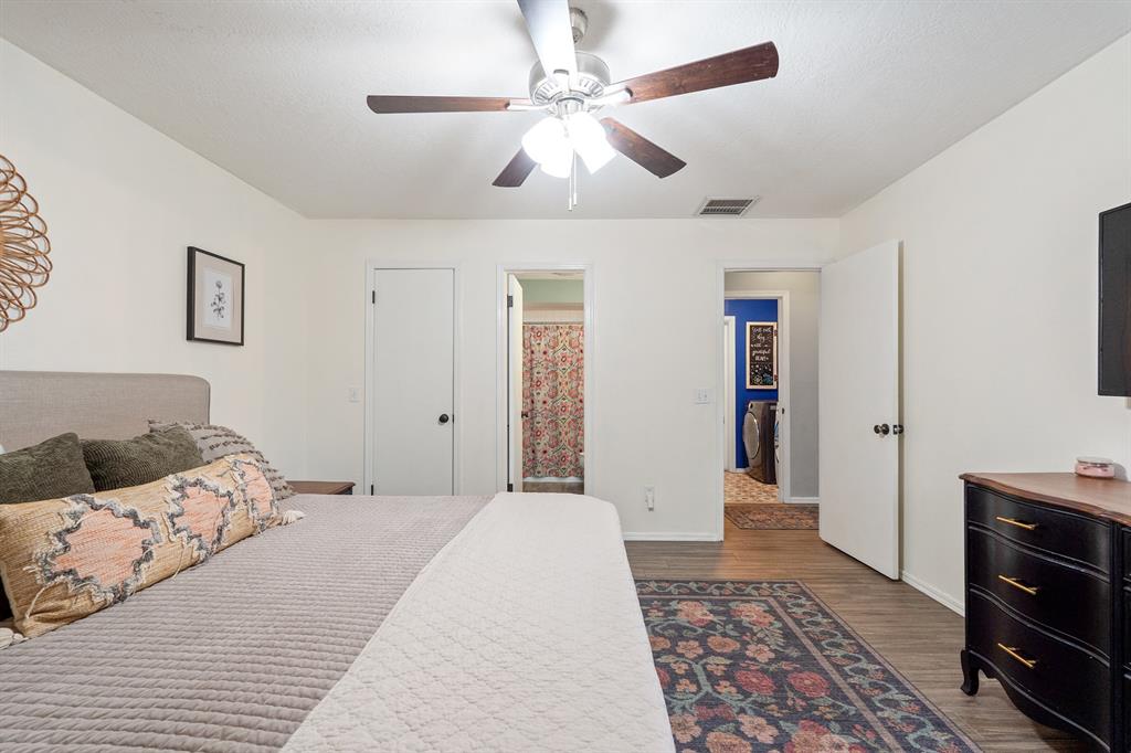 Furnished bedroom with a large bed, patterned rug, ceiling fan, and open doors to adjoining rooms.