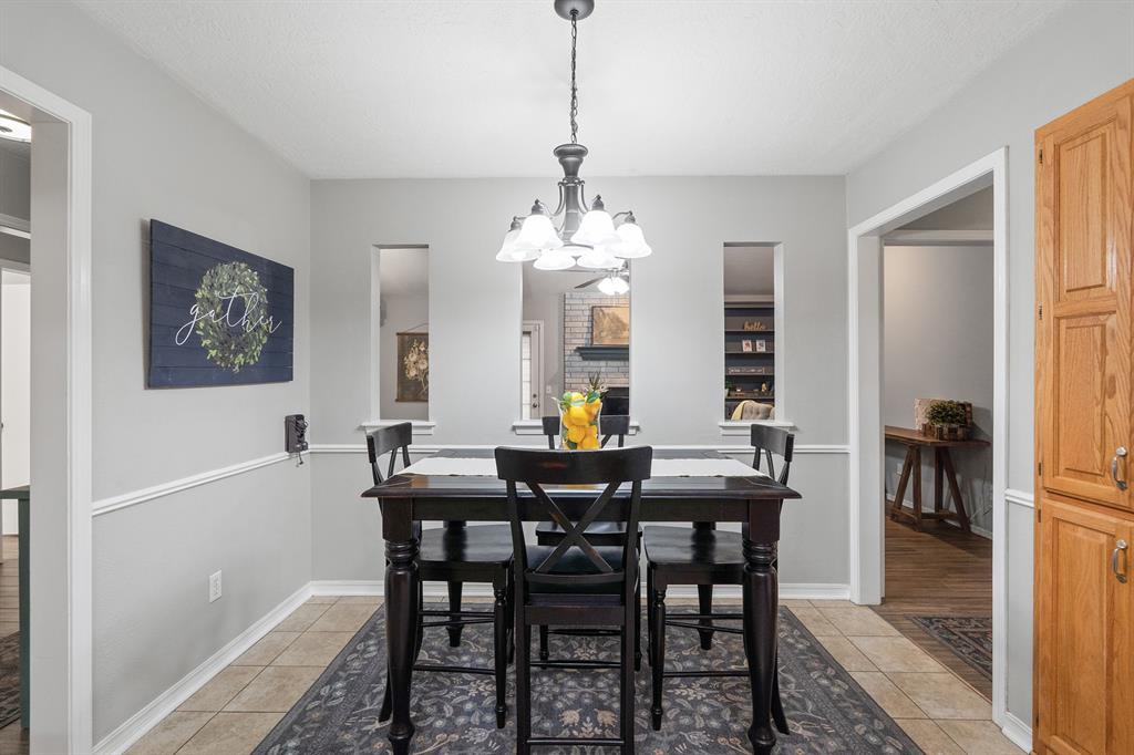 Dining room with a dark wood table beneath a chandelier and a tall wooden pantry cabinet.