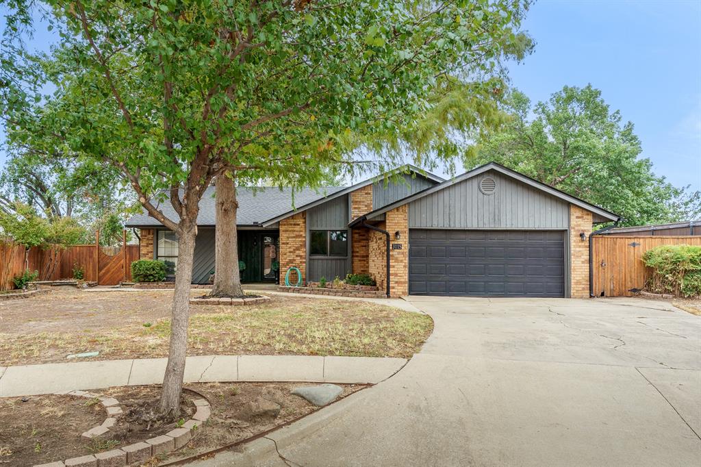 Single-story brick and gray-sided home with a two-car garage and mature front-yard tree.