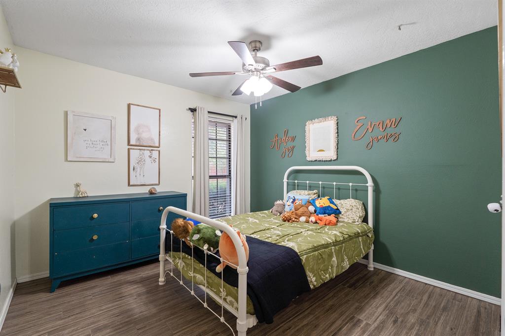 Bedroom with a white metal bed, green accent wall, blue dresser, and ceiling fan.