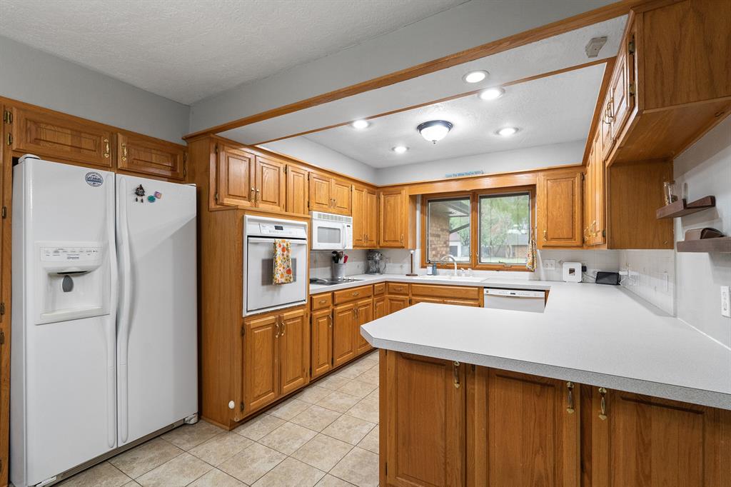 Kitchen with honey-colored cabinets, white countertops, a central island, and a window above the sink.