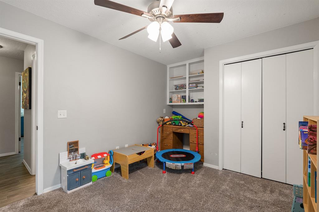Children’s playroom with built-in shelves, a small trampoline, and double closet doors.