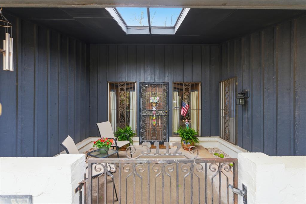 Covered entry porch with a skylight, decorative metal doors, and a gate marked 3112.