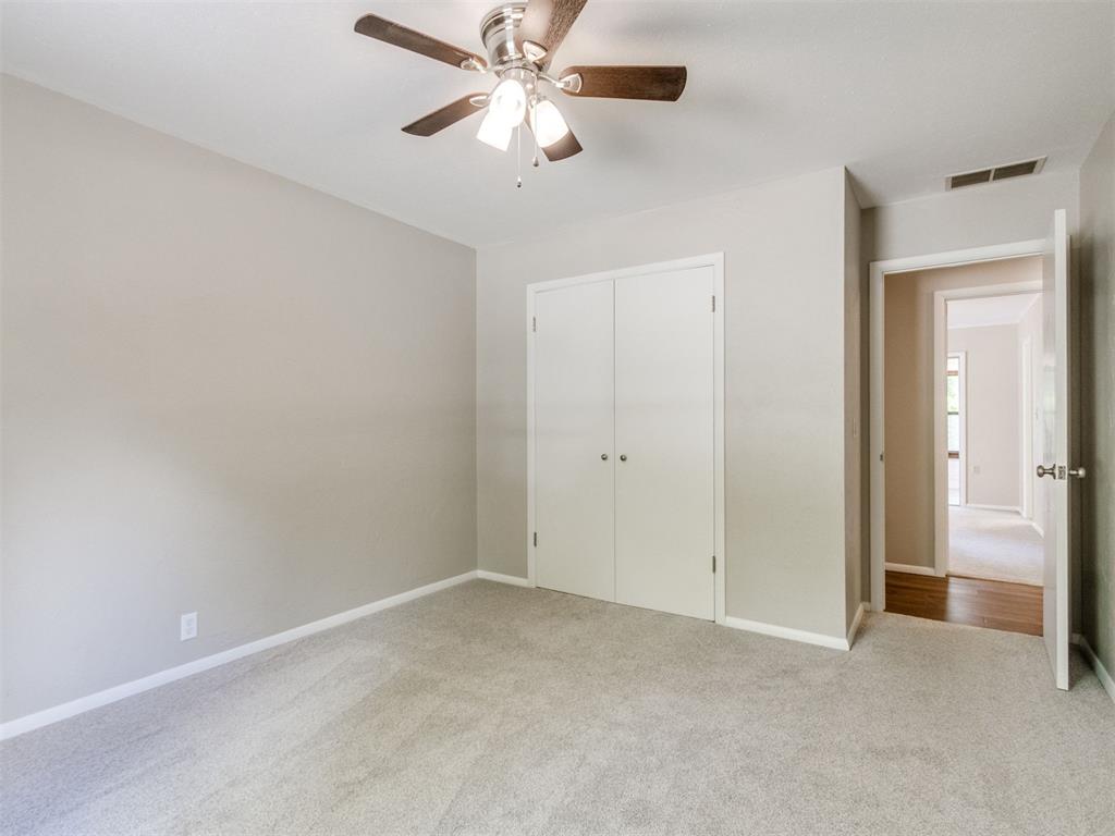 Empty carpeted bedroom with a double-door closet and ceiling fan.