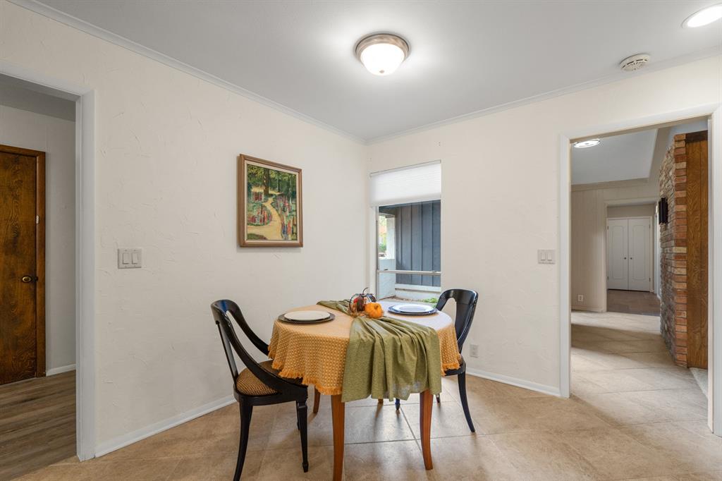 Dining room with a table set for two beside a window and open doorways to adjoining rooms.