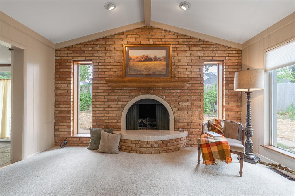 Living room with a vaulted ceiling and a large brick fireplace flanked by narrow windows.