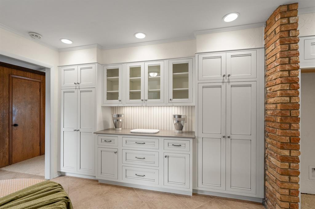Bedroom with built-in white cabinets and drawers beside a brick column.