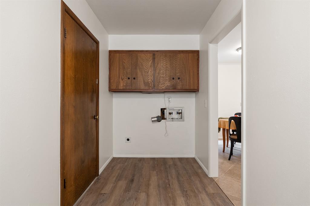 Laundry area with wooden cabinets, washer hookups, and a doorway to the dining room.