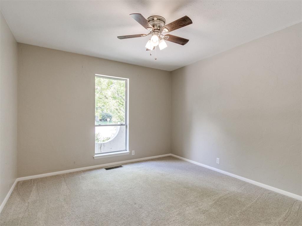 Empty bedroom with beige carpet, a single window, and a ceiling fan.