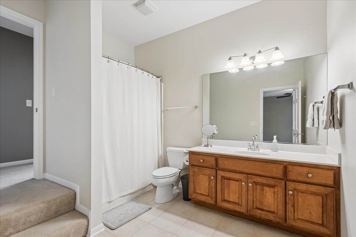 Bathroom with a wide wood vanity, large mirror, and curtained bathtub.