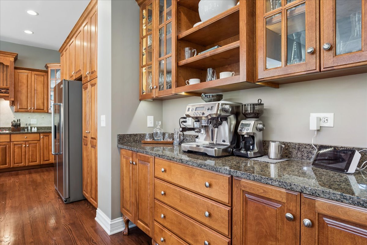 Kitchen with warm wood cabinets, granite counters, and an espresso machine and grinder.