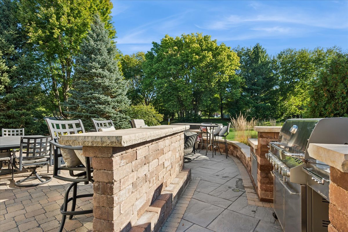 Stone patio with outdoor dining, a built-in brick counter, and stainless steel grill.