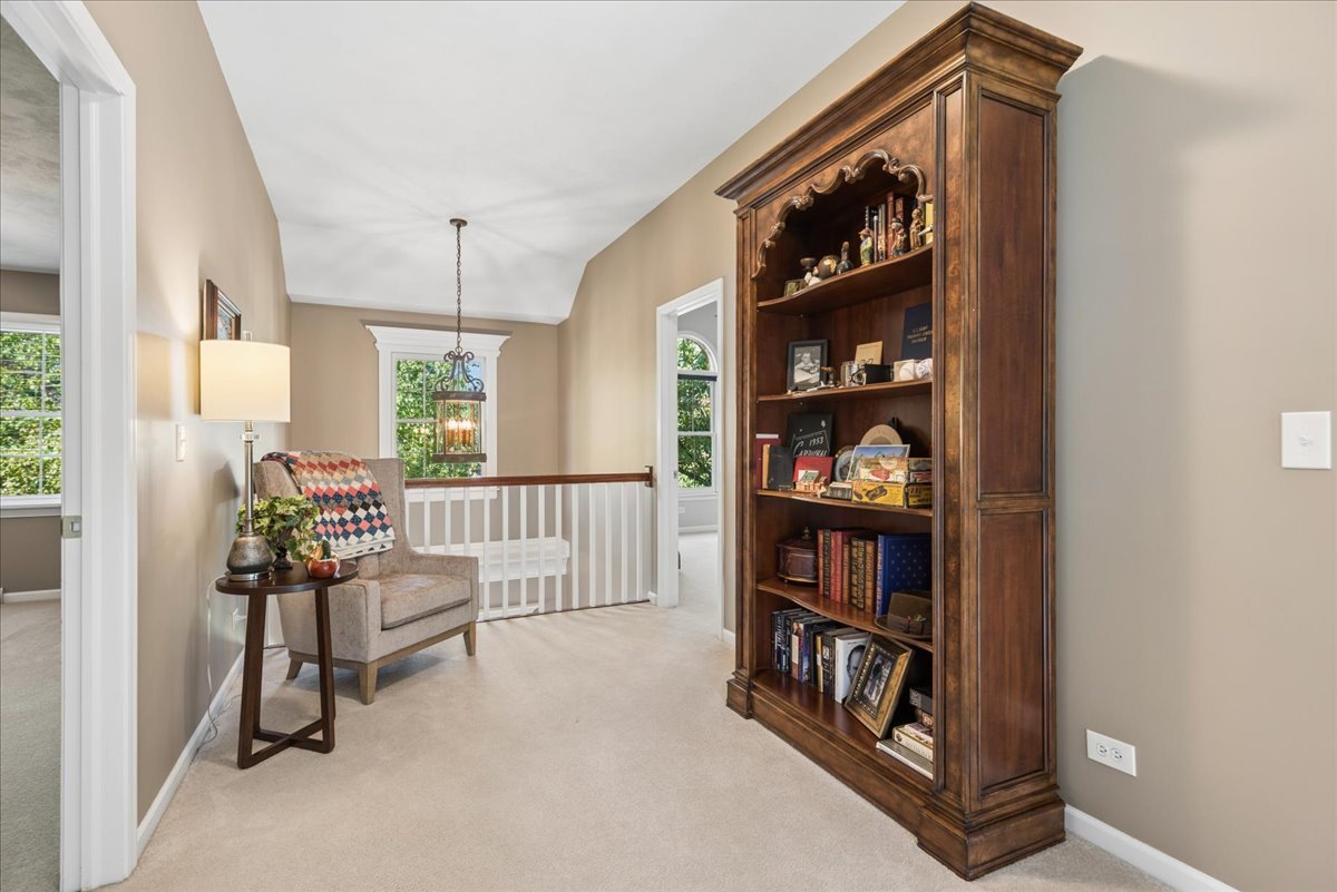 Upstairs landing with a tall carved bookcase and a small armchair seating nook.