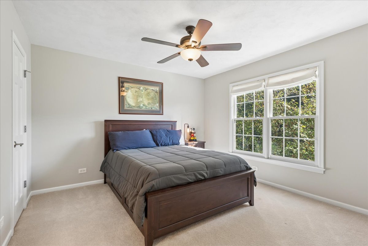 Bedroom with a dark wood bed and large windows overlooking leafy greenery.