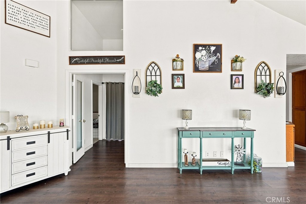 Furnished entryway with dark wood floors, a teal console table, and an open doorway.