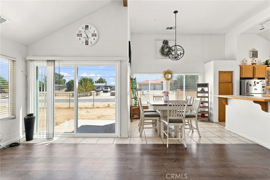 Dining area with a white table, black chandelier, and sliding glass doors opening to a dry yard.