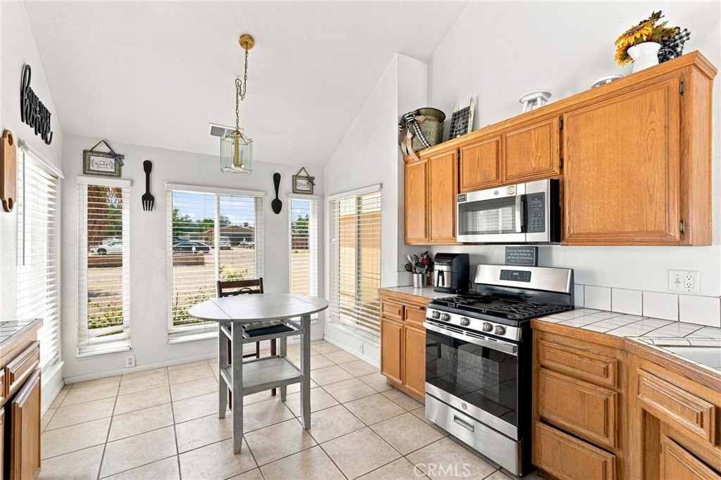 Kitchen with honey-colored cabinets, stainless steel appliances, and a small table by the windows.