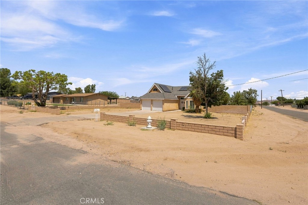 House at 18170 Capri with attached garage, low masonry walls, and a dry sandy yard.