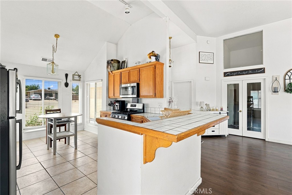 Bright kitchen with wood cabinets, stainless appliances, and a tiled peninsula counter.
