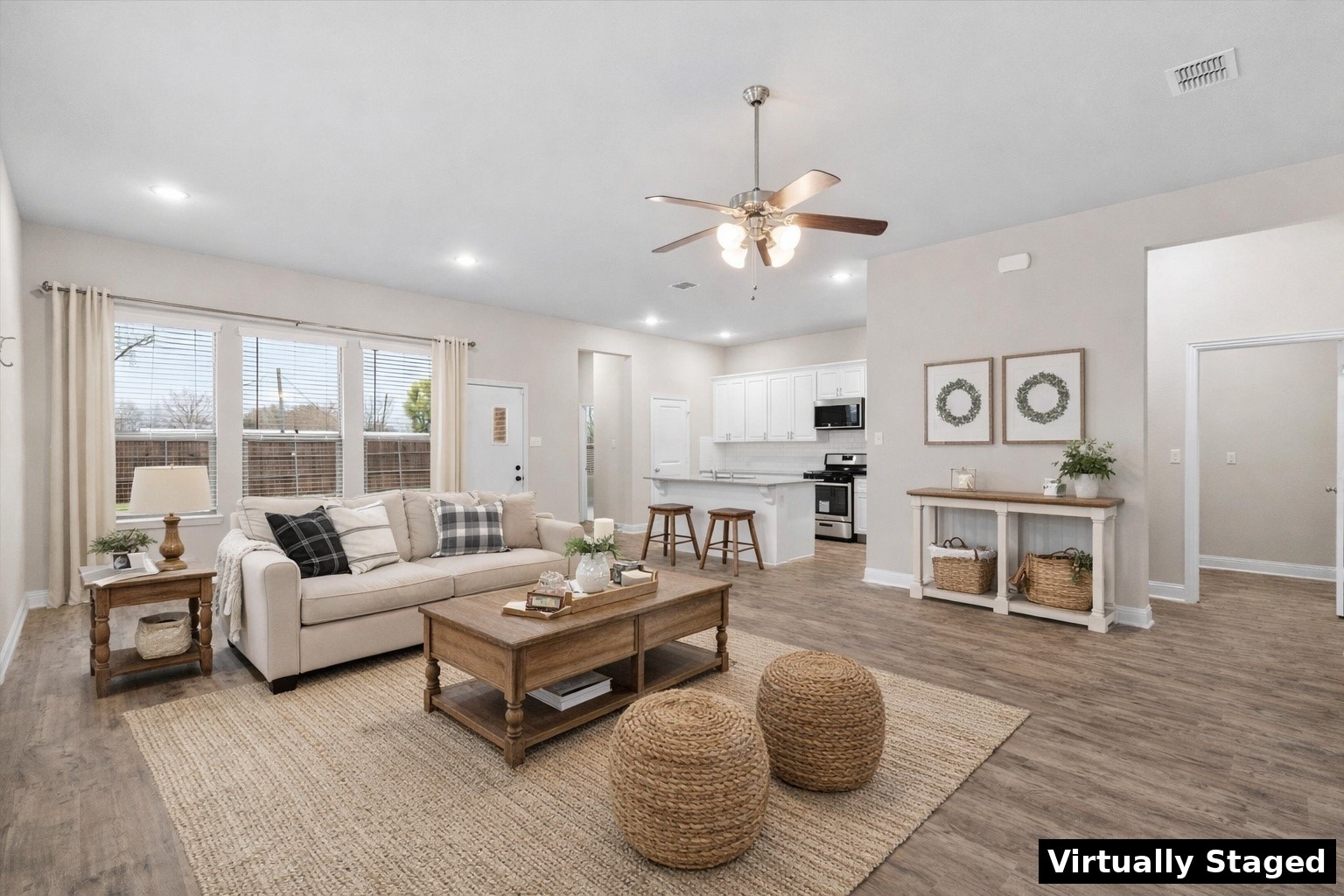 Virtually staged open-plan living room and kitchen with a cream sofa, white cabinets, and breakfast bar.