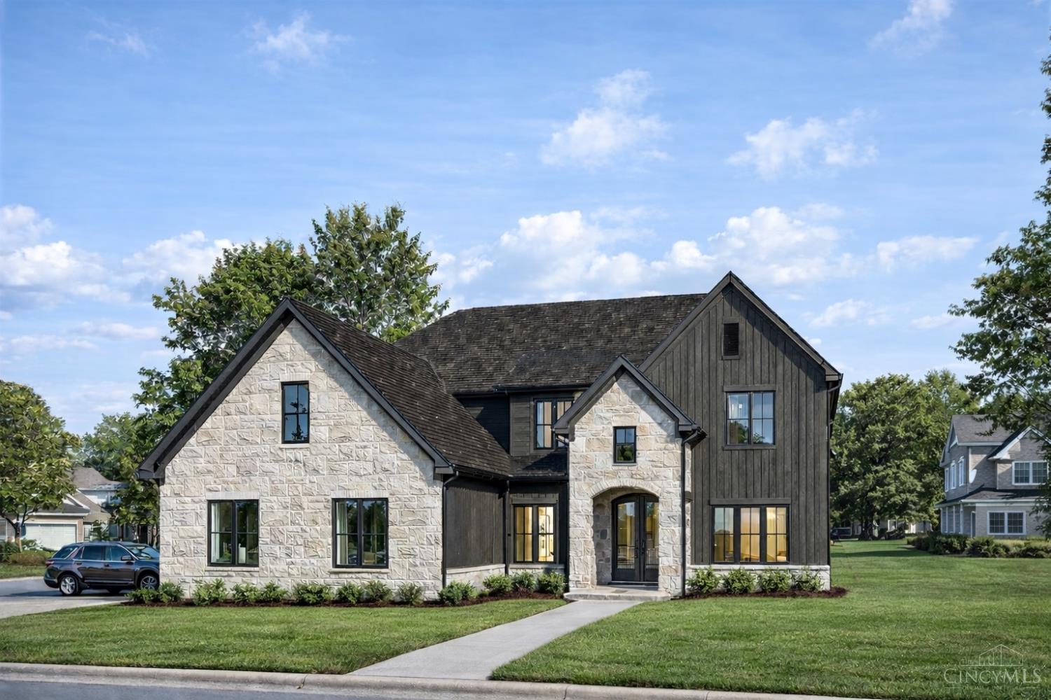 Home with pale stone and dark siding, multiple gables, and a broad front lawn.