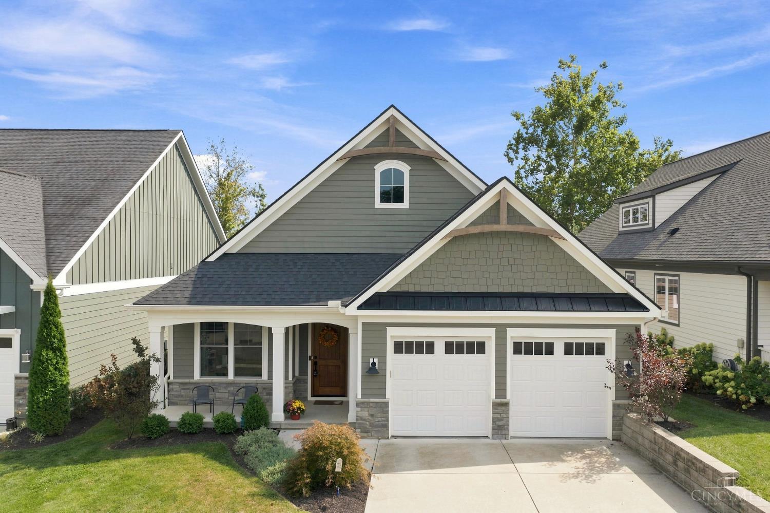 Gray gabled home with a covered porch, stone accents, and a two-car garage.
