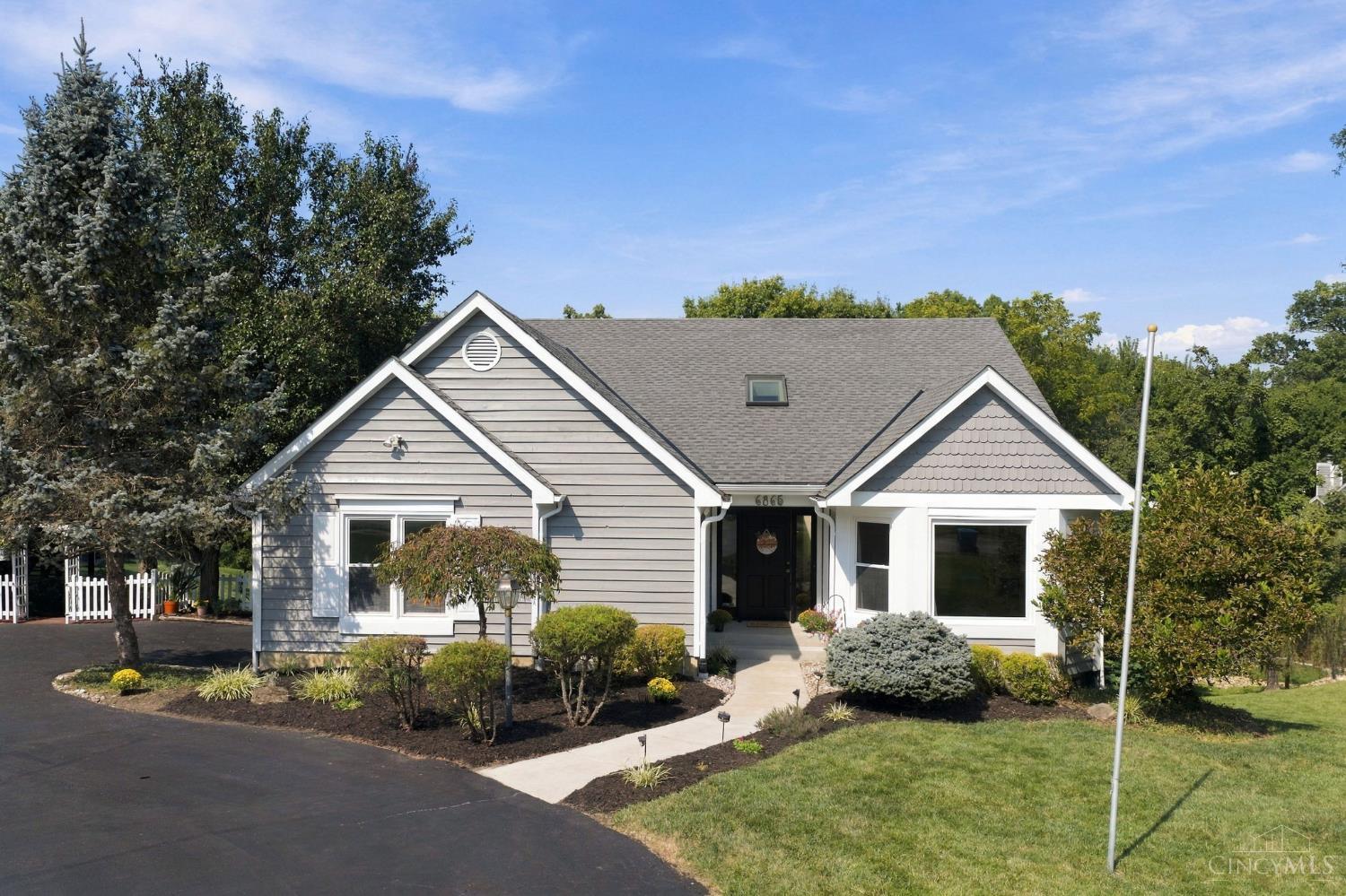 Gray single-story home with white trim, landscaped front beds, and a curved walkway to the entrance.