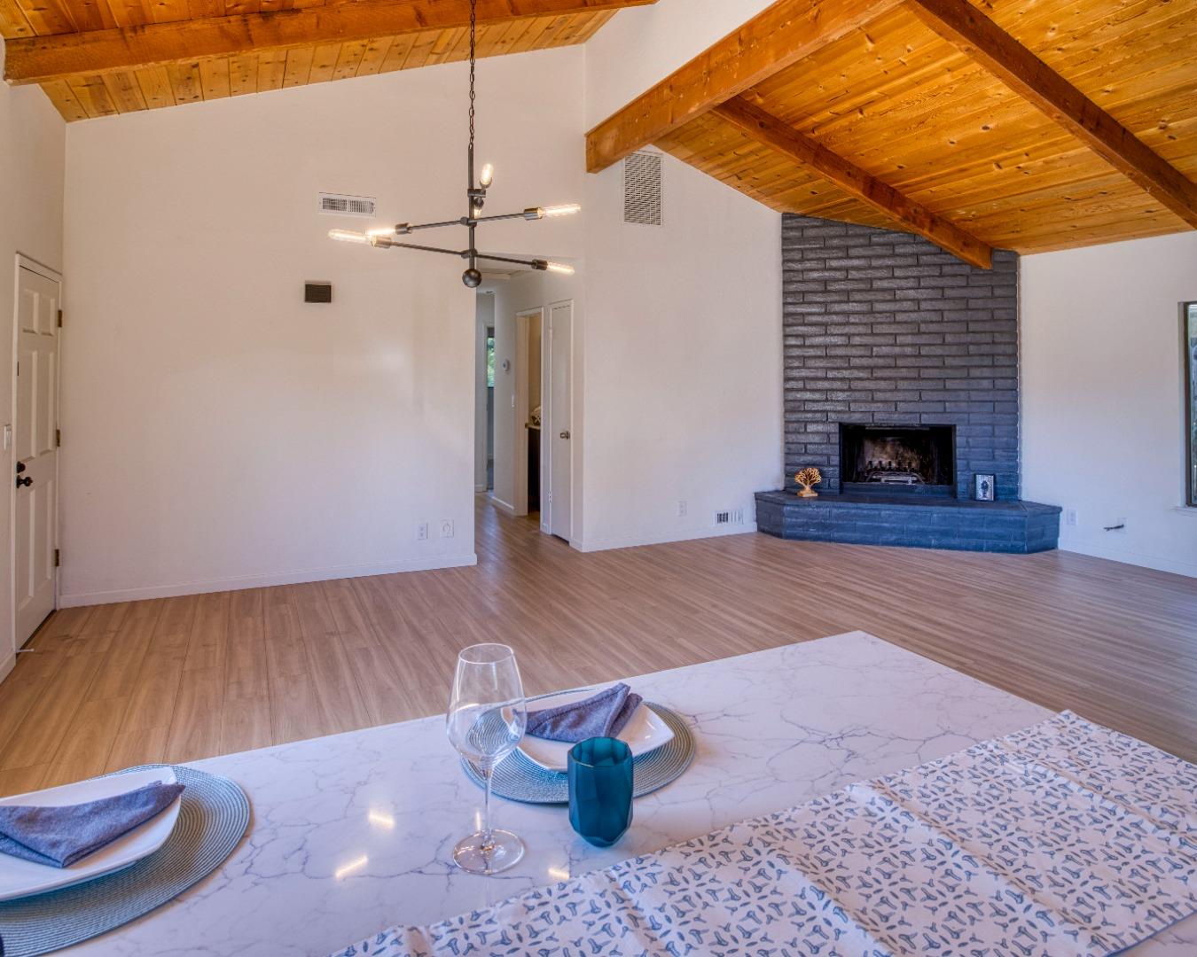 Living room with a vaulted wood ceiling, exposed beams, and a dark brick fireplace.
