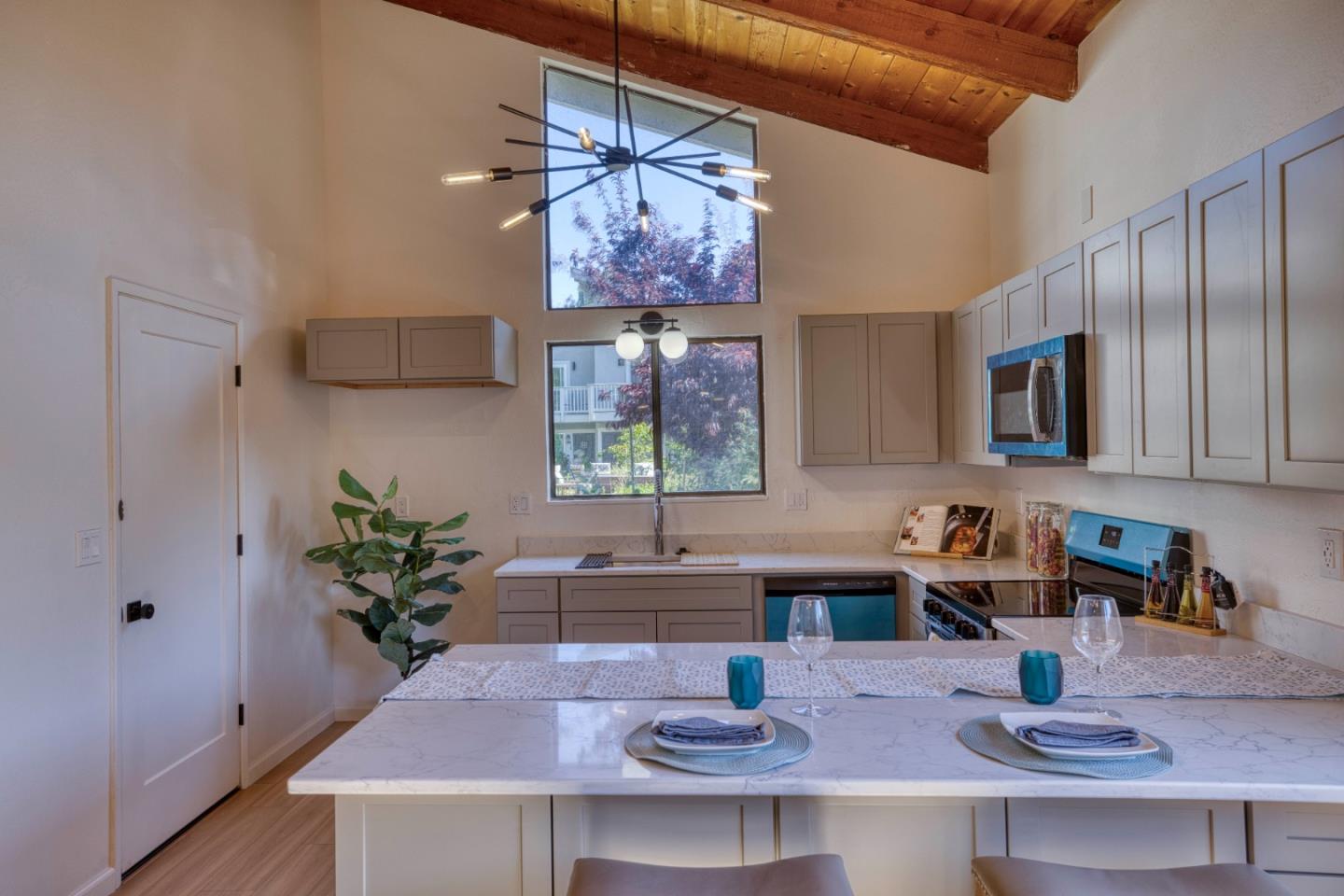 Modern kitchen with a marble island set for two beneath a vaulted wood ceiling.