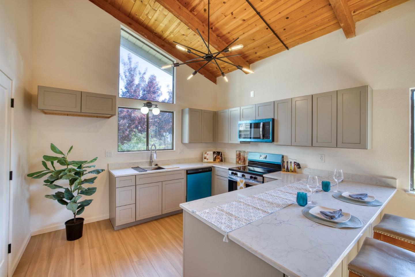 Kitchen with a large set island, pale cabinetry, and a vaulted wood-plank ceiling.